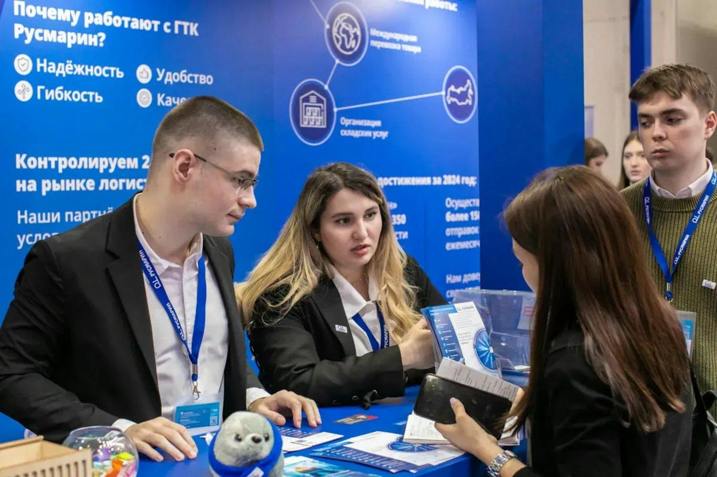 Nhân viên tư vấn khách tại booth triển lãm màu xanh